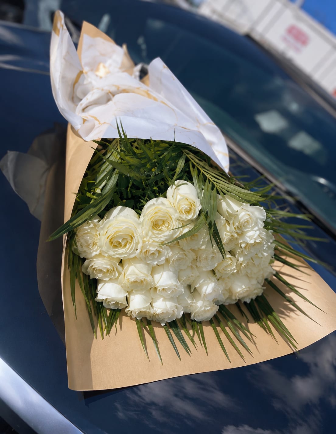 Bouquet of white roses wrapped in brown and white paper