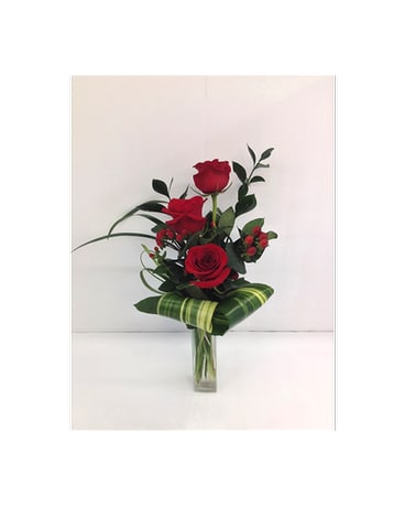 Red roses arranged in a clear glass vase with striped leaf wrapping