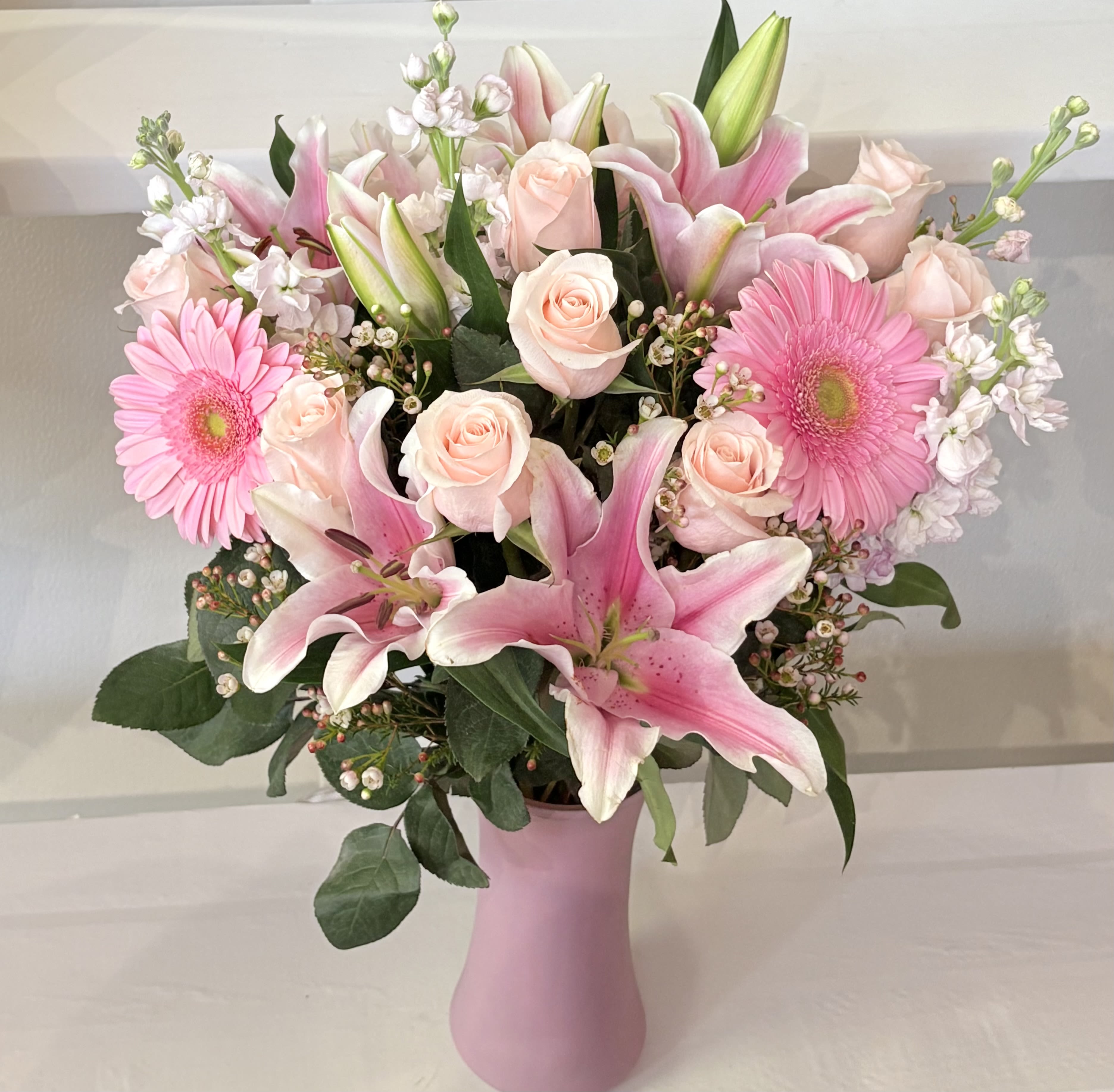 Pink lilies, roses, and gerbera daisies in a pink vase