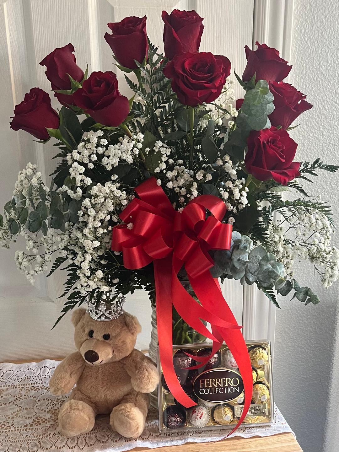 Red roses in a vase with baby’s breath, a teddy bear, and chocolates