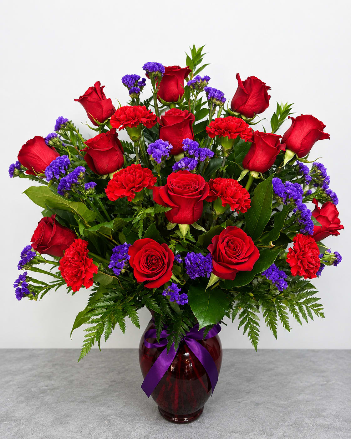 In Vogue  - 12 red roses, 6 carnation, and premium assorted statice filler. Arrangement is delivered as shown.