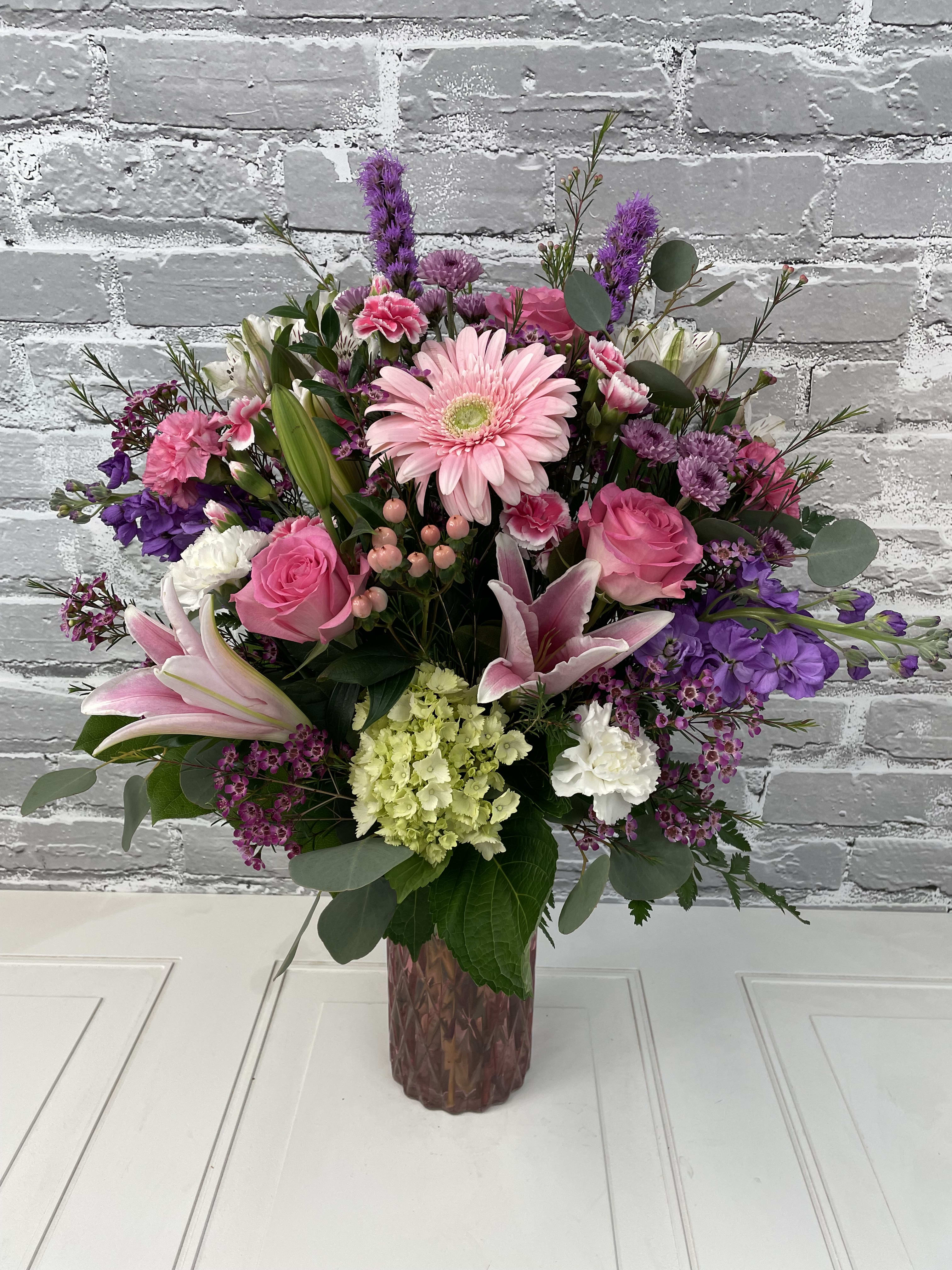 Pink and purple mixed flower arrangement in a glass vase