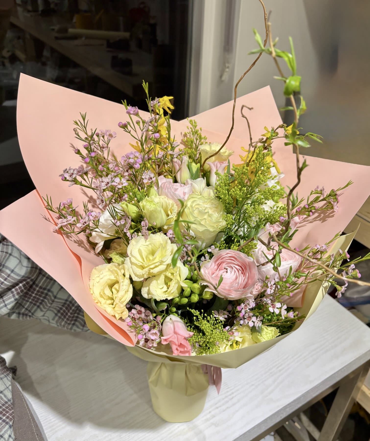 Pastel bouquet of pink, yellow, and white flowers wrapped in paper
