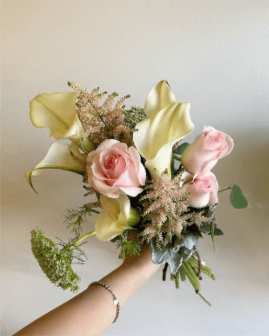 Handheld bouquet with pink roses and pale yellow calla lilies