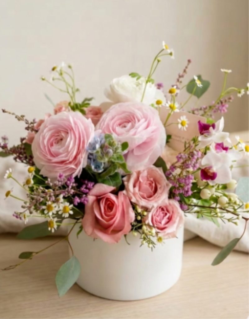 BP43 - Ranunculus Blossom  - A beautiful mix of delicate ranunculus and classic roses in white container.