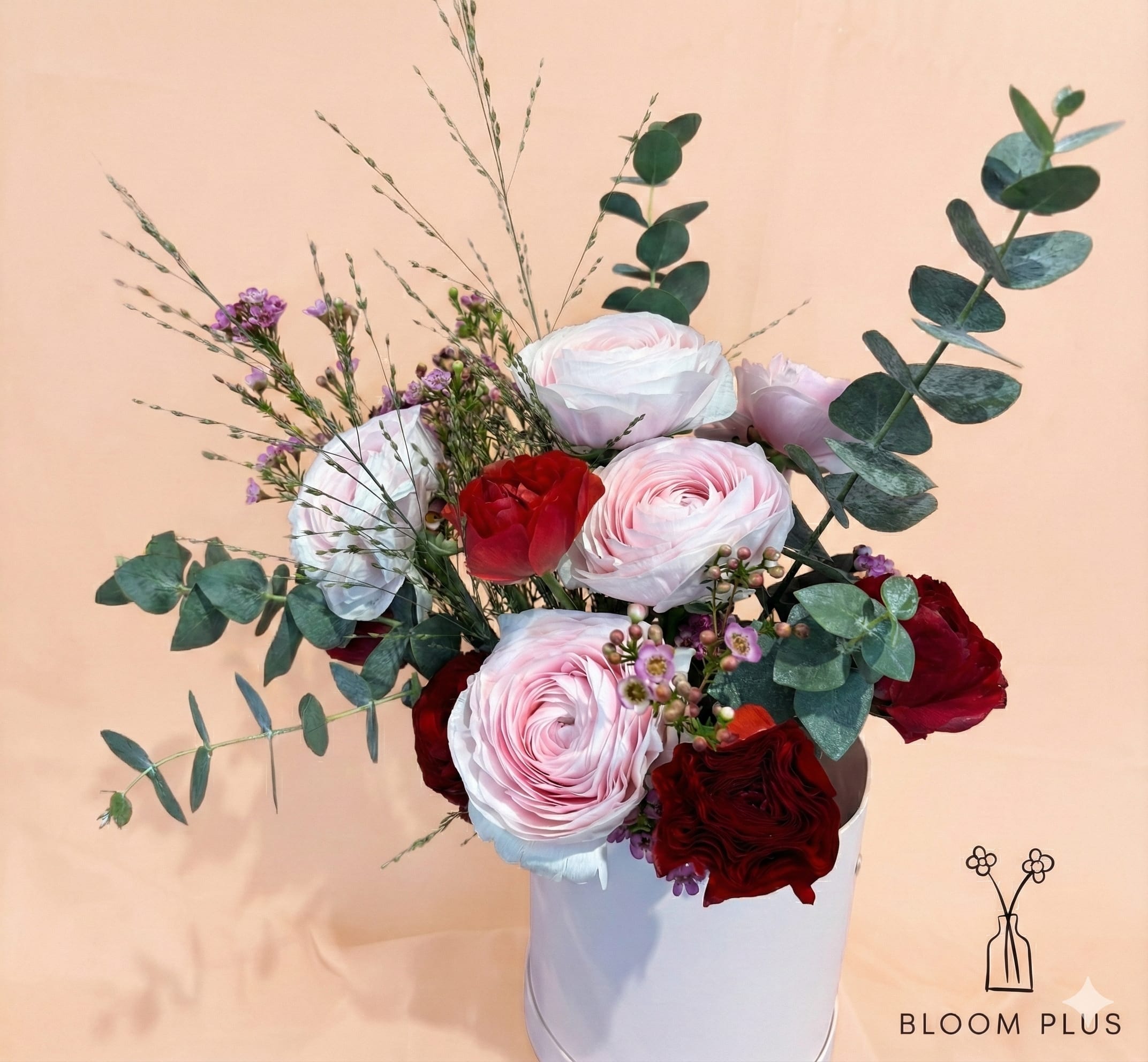 Bouquet of pink and red flowers in a white container
