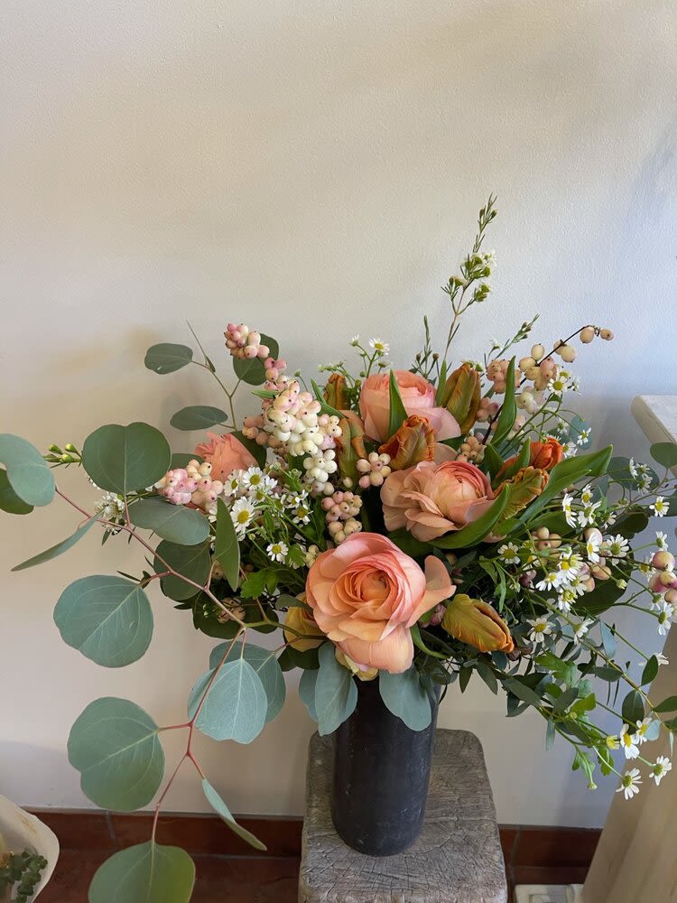 Peach roses and small white daisies in a black vase