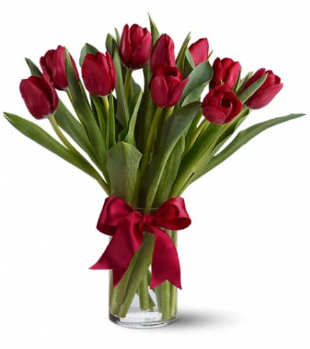 Red tulips in a clear glass vase tied with a red ribbon