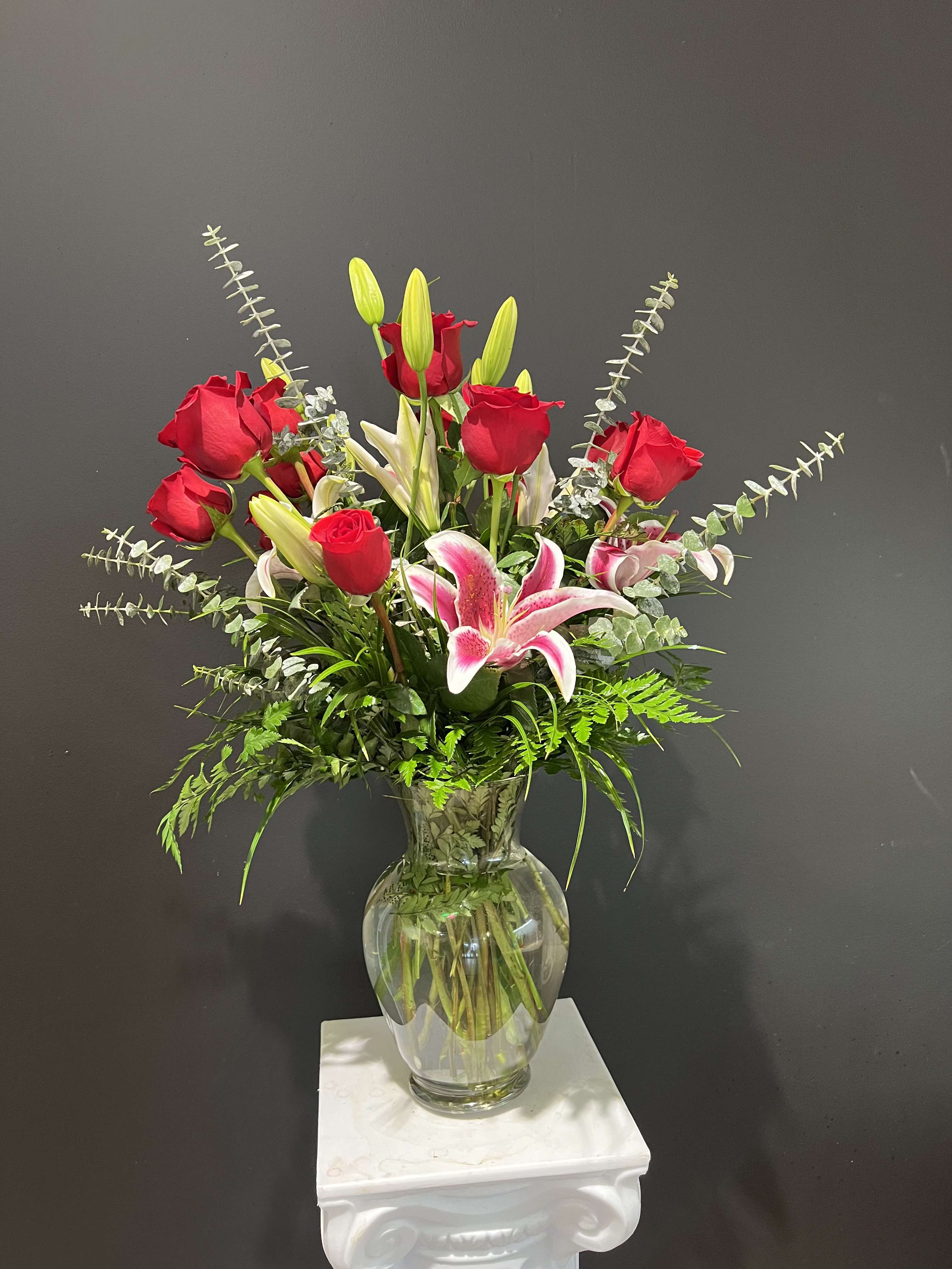 Red roses and pink lilies in a clear glass vase