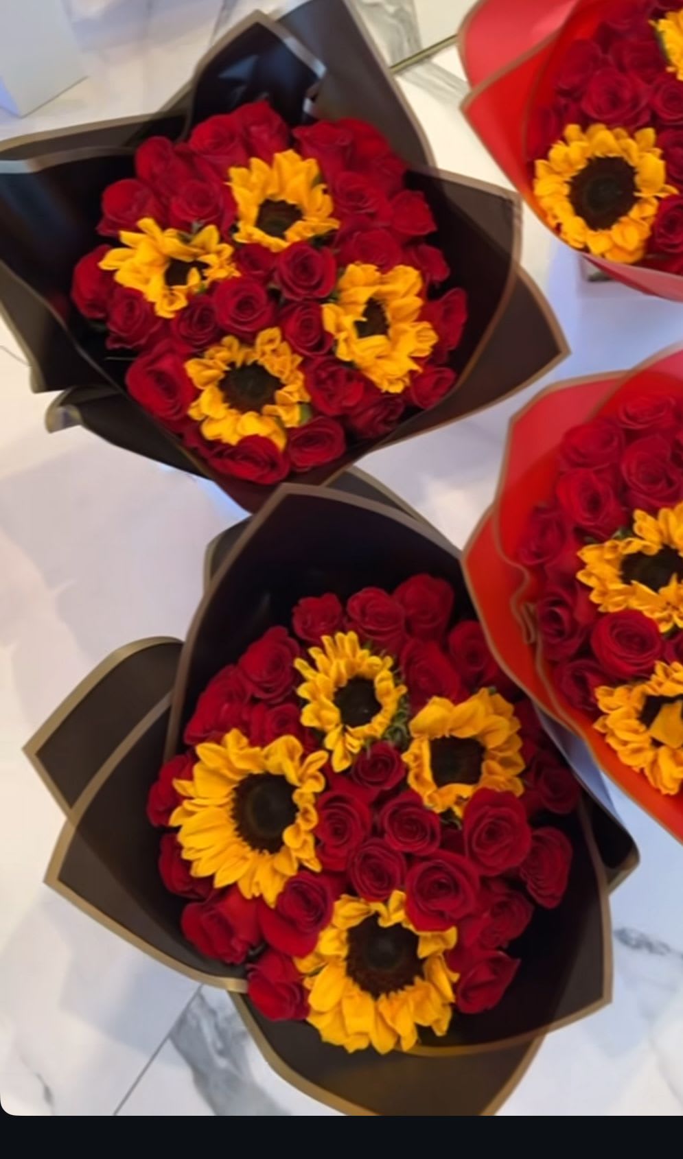 Bouquets of red roses and yellow sunflowers in dark wrapping