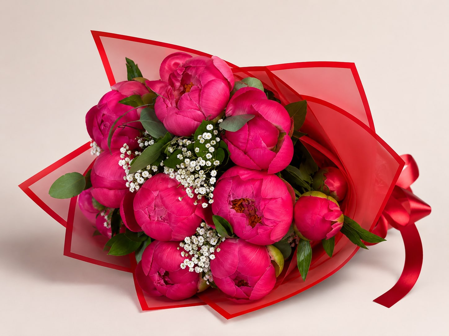 Peony Kiss Bouquet - A luxurious hand-tied bouquet of vibrant coral peonies wrapped in elegant red translucent paper and finished with a satin ribbon. This bouquet features lush, premium peony blooms accented with delicate baby’s breath and fresh greenery for a romantic, timeless look. Perfect for Mother’s Day, birthdays, anniversaries, or simply making someone feel special. Limited seasonal availability.