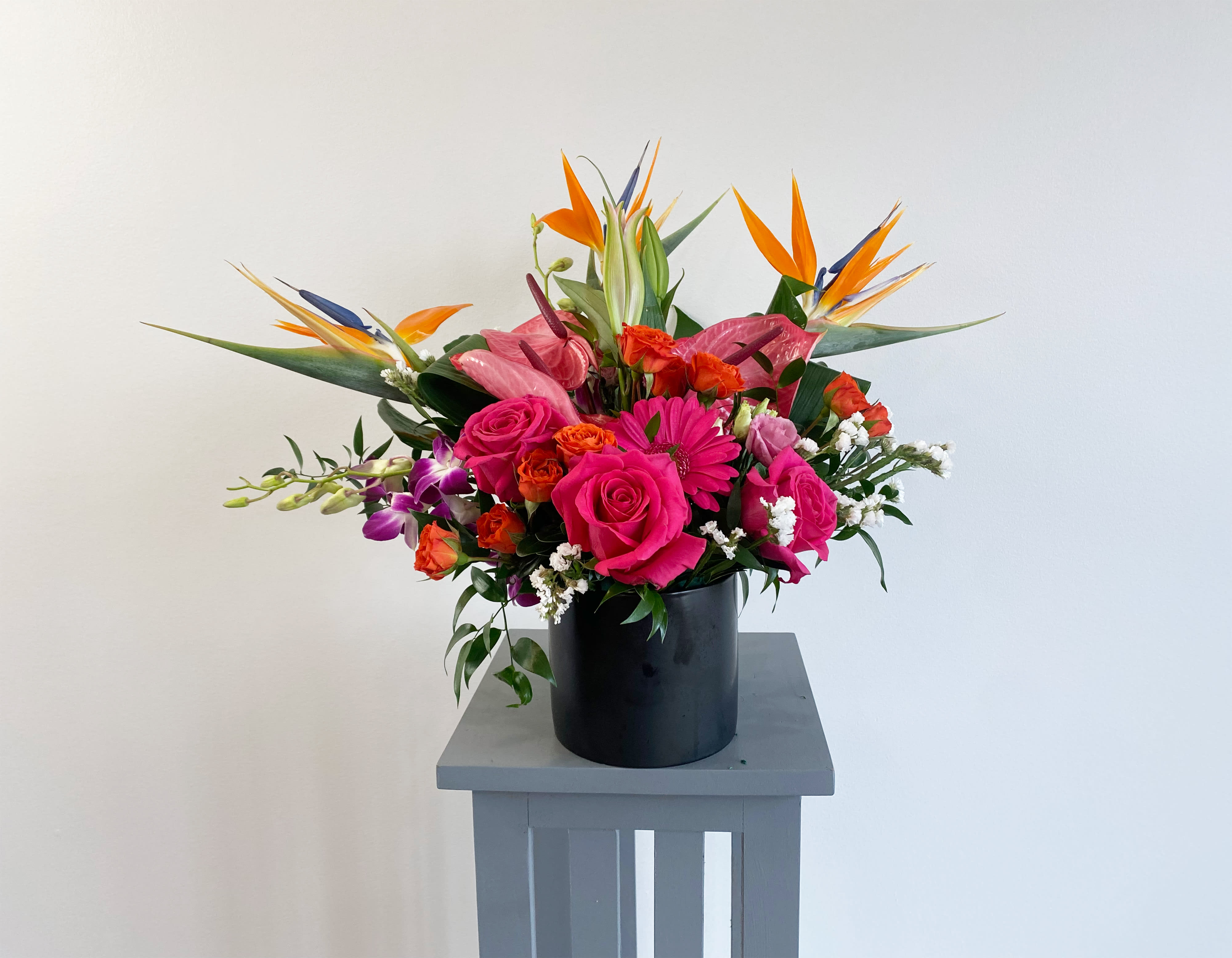 Bright tropical bouquet with pink roses in a black vase