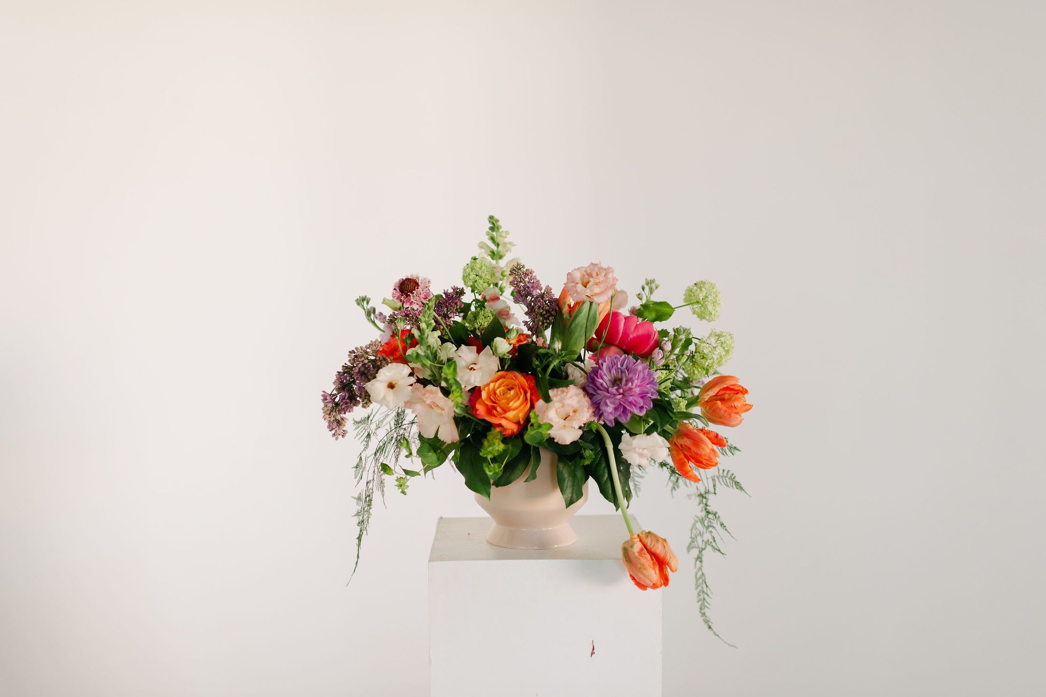 Deluxe Spring Centerpiece - A lush blend of peaches, blush pinks, soft lavenders, and fresh greens, this statement centerpiece is the perfect addition to a spring brunch or just to bring some extra sunshine into your home!  Filled with premium blooms such as romantic peonies, dramatic dahlias, fluffy lisianthus, lush tulips and fragrant lilac  Occasionally, we may need to substitute individual blooms due to daily and seasonal availability so arrangements may not look exactly as pictures, but we will always substitute with similar flowers where possible.