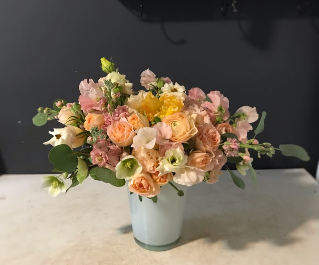 Pastel bouquet of peach, pink, and white flowers in a pale vase