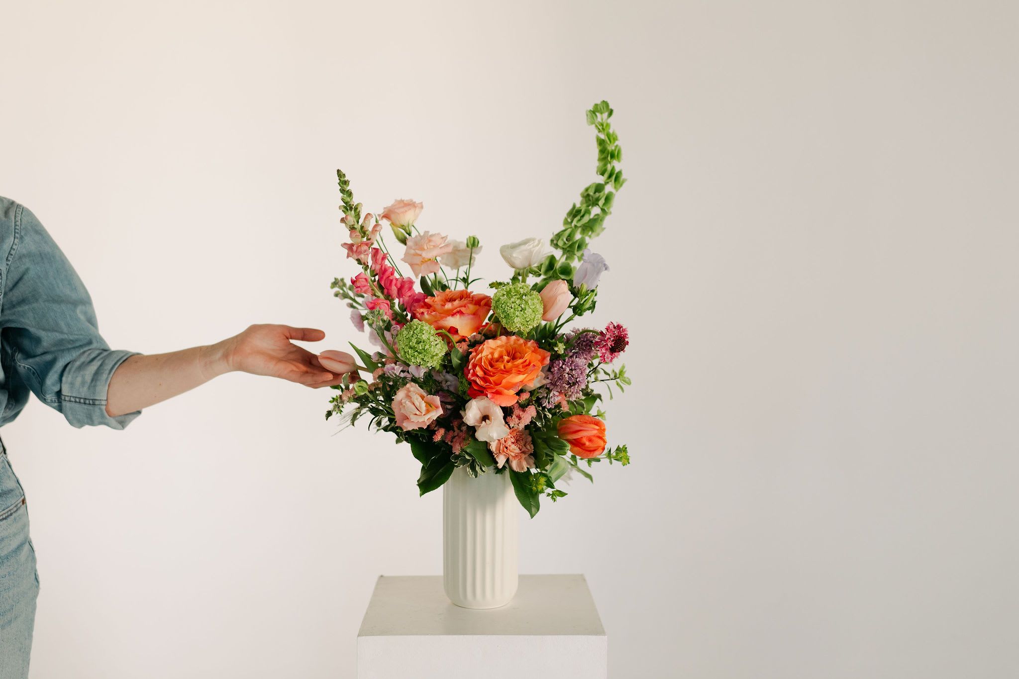 Deluxe Spring Vase Design - A lush blend of peaches, blush pinks, soft lavenders, and fresh greens, this statement vase design is perfect to bring some extra sunshine into your home!  Filled with premium blooms such as romantic ranunculus, bright roses, fluffy lisianthus, lush tulips and fragrant lilac  Occasionally, we may need to substitute individual blooms due to daily and seasonal availability so arrangements may not look exactly as pictures, but we will always substitute with similar flowers where possible.
