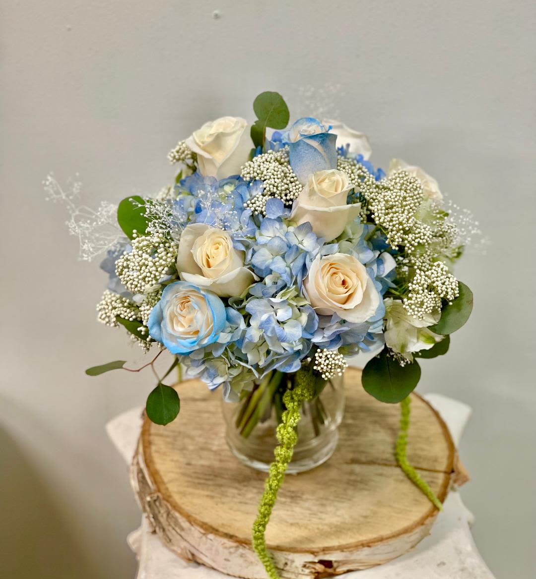 Blue hydrangea and cream roses in a clear glass vase