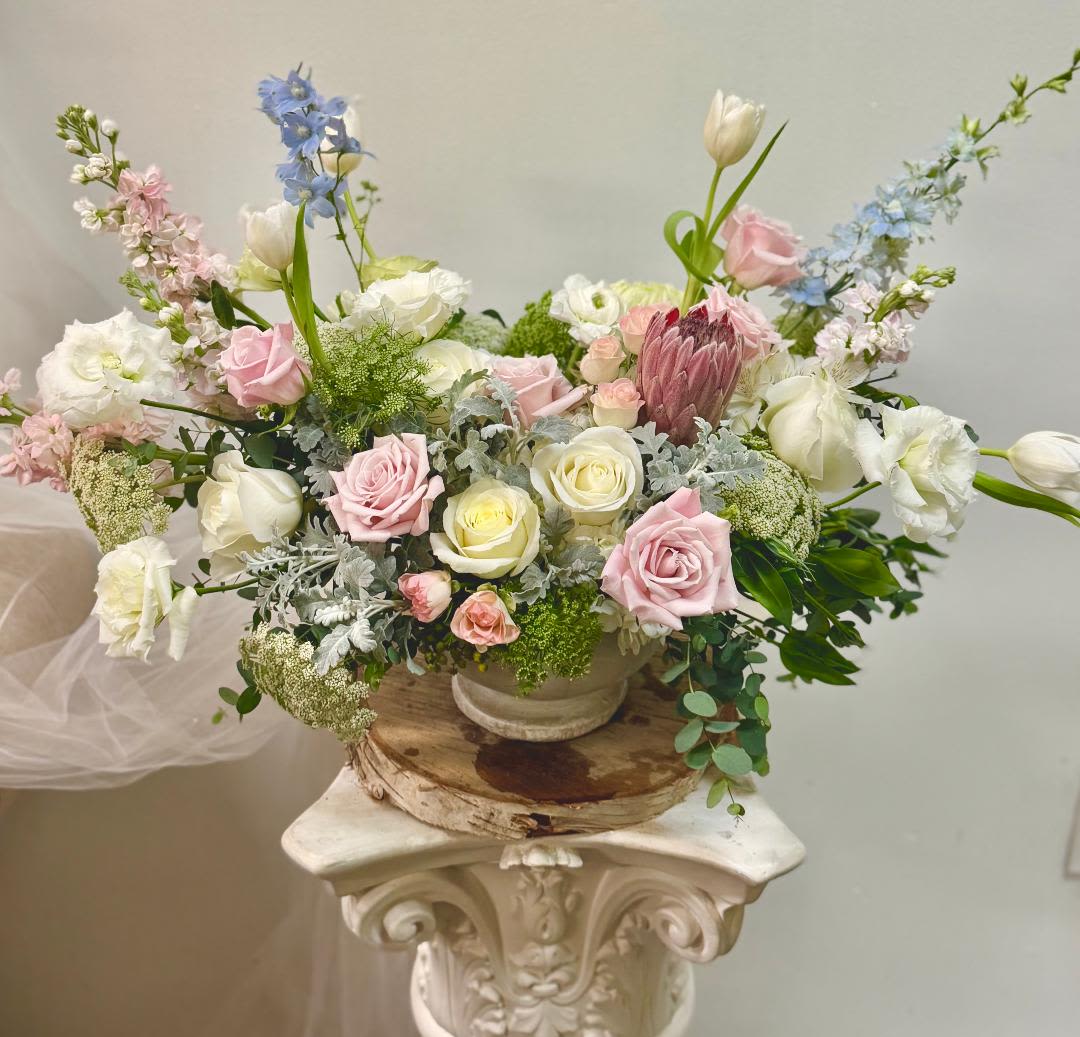 Pastel floral arrangement with roses, tulips, and delphinium in a low bowl