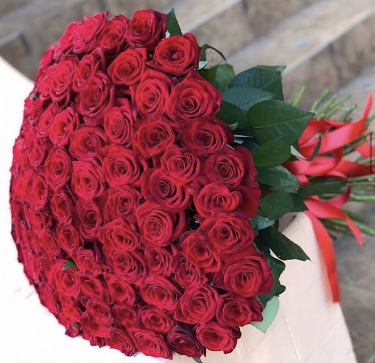 Large bouquet of red roses with green leaves and red ribbon
