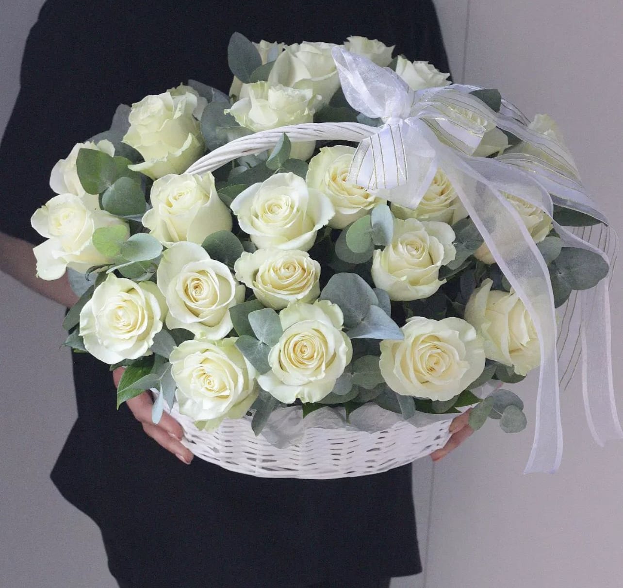 Basket of white roses with eucalyptus and a white ribbon bow