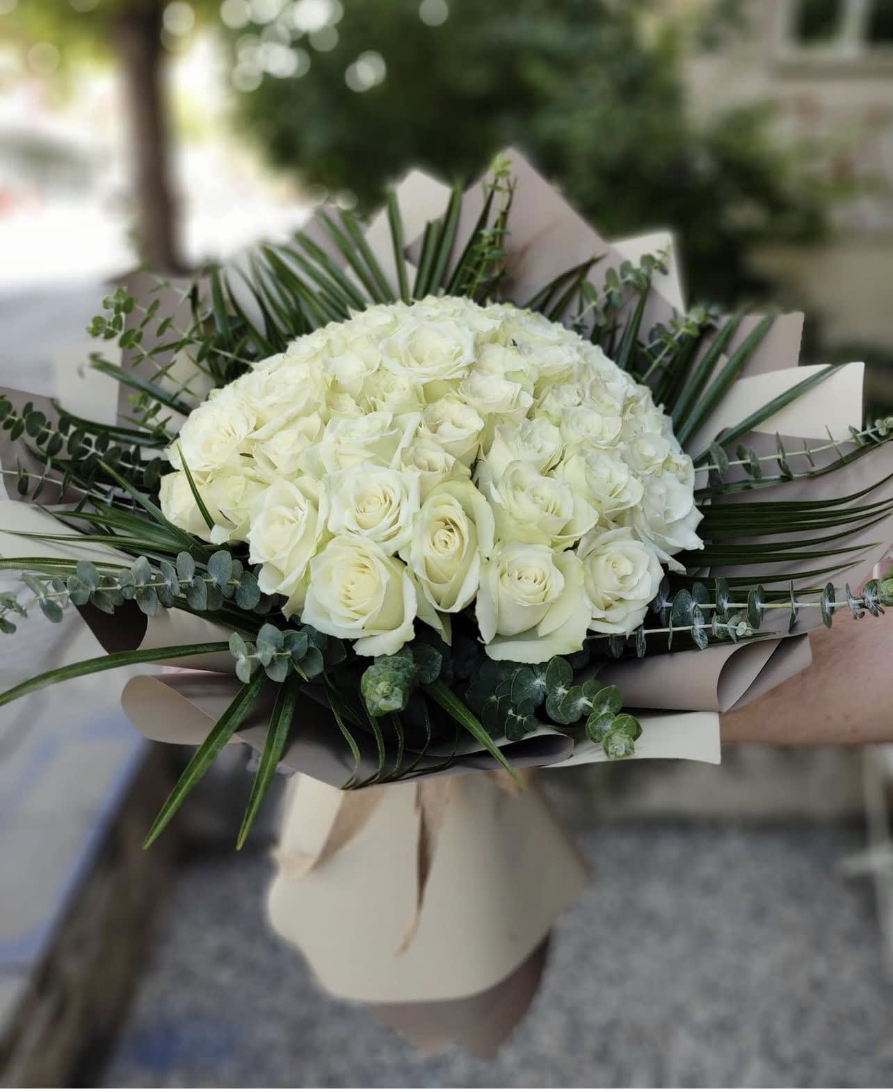 Bouquet of white roses with greenery and beige wrapping