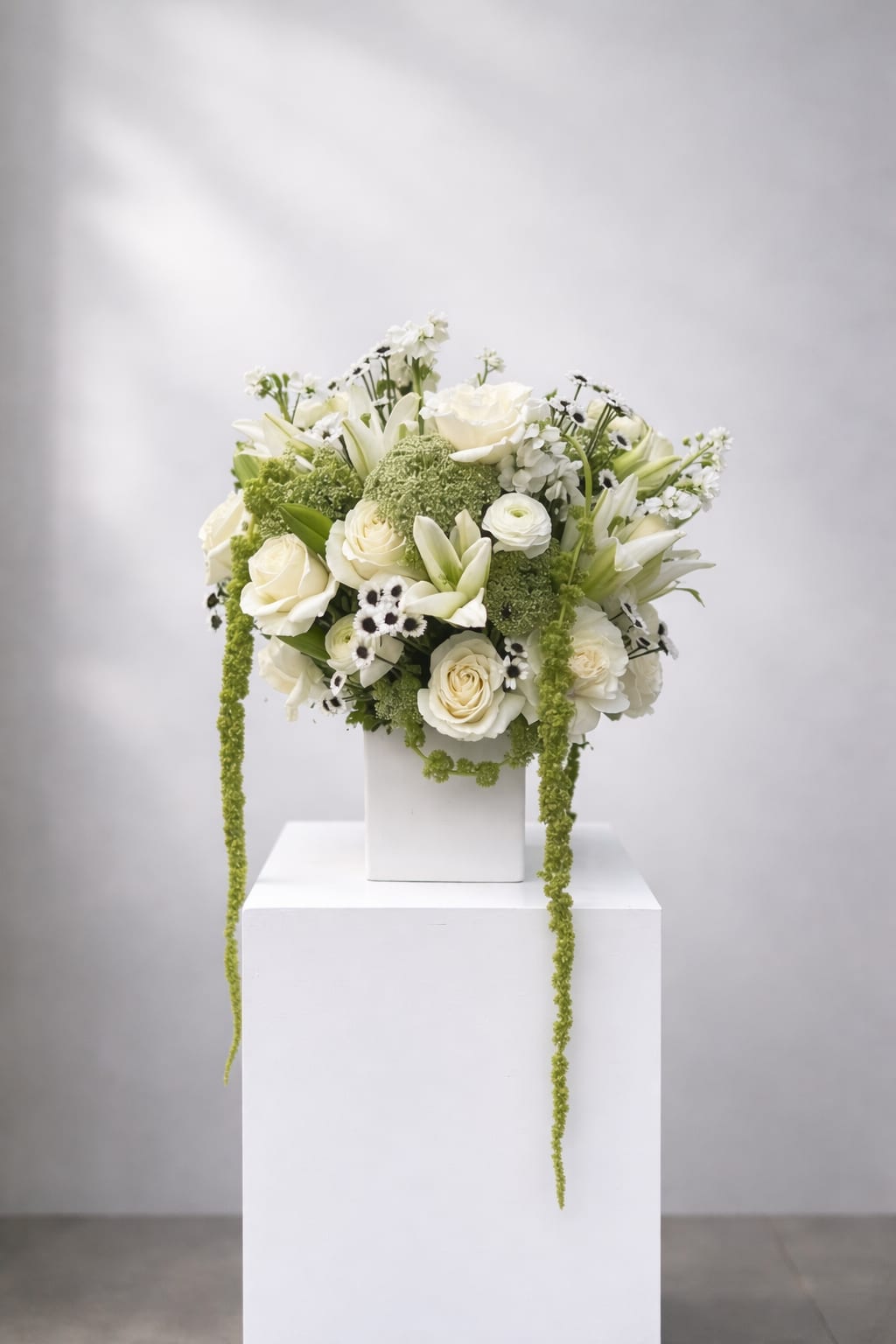 White floral arrangement with roses and lilies in a white vase