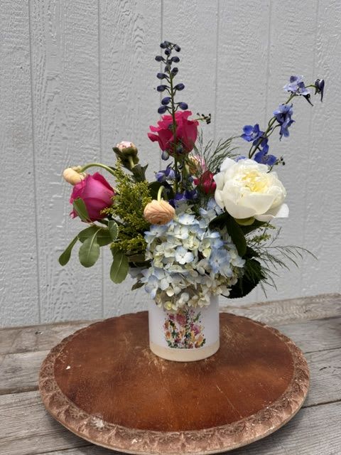 First Lady Bouquet - First Lady Bouquet  An elegant and refined arrangement designed to honor the strength, grace, and beauty of the women who lead with love.  Presented in a Mom planter, First Lady Bouquet features a sophisticated blend of larkspur, peony, ranunculus, roses, blue hydrangea, and solidago. The combination of soft, lush blooms and structured accents creates a design that feels both classic and distinguished.  Each arrangement is thoughtfully styled to make a statement while still feeling warm and heartfelt, offering a beautiful balance of elegance and meaning.  Designed for Mother’s Day, First Lady Bouquet is a stunning way to celebrate her with something as timeless and remarkable as she is.