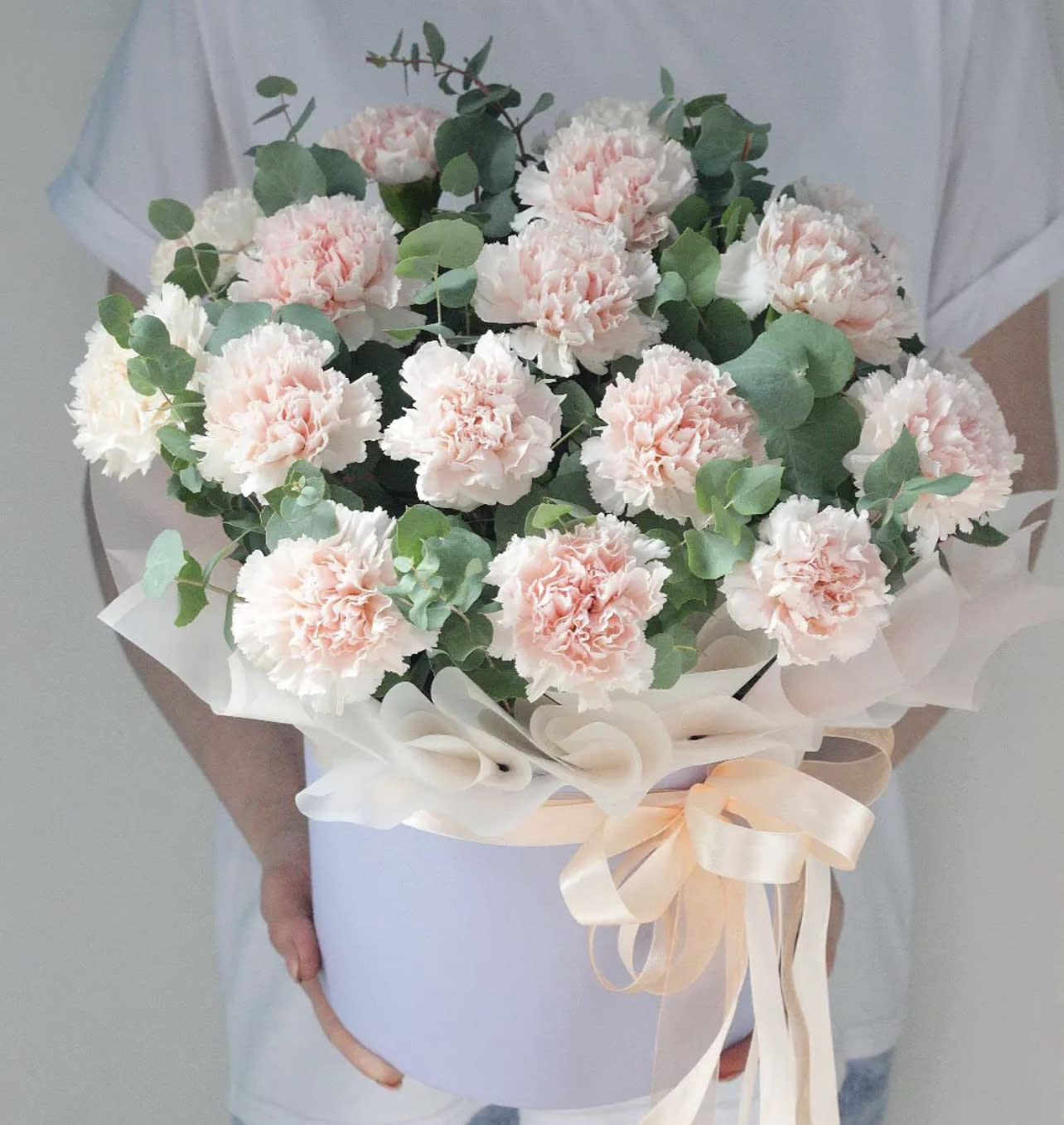 Bouquet of pale pink carnations with eucalyptus in a lavender box
