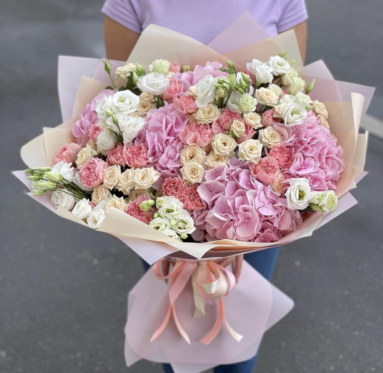 Large bouquet of pink and white flowers wrapped in pastel paper