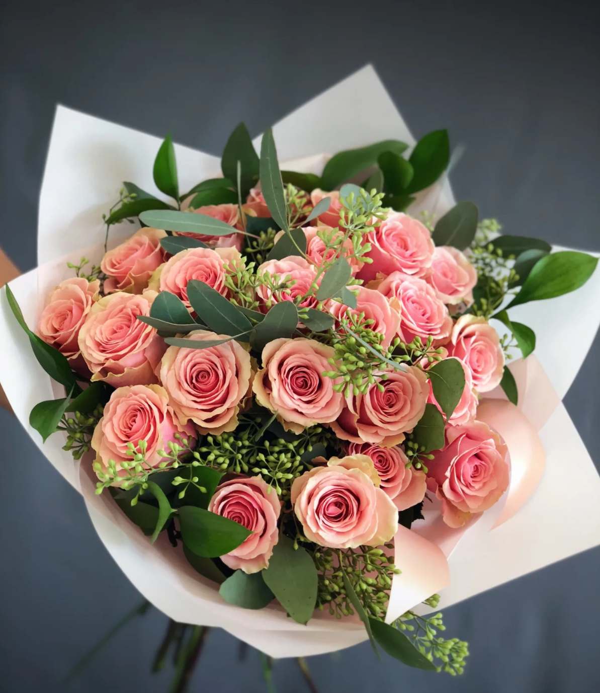 Bouquet of pink roses with white wrapping and greenery