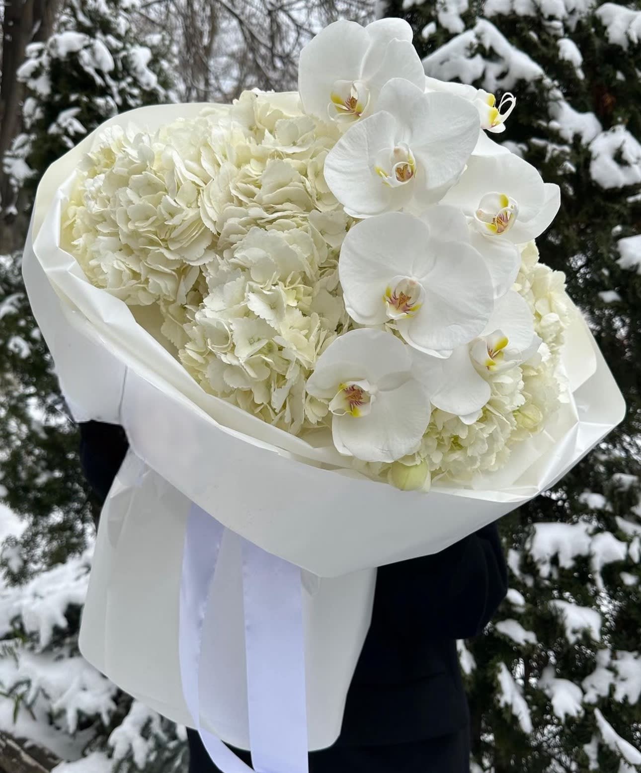 White hydrangea and orchid bouquet wrapped in white paper