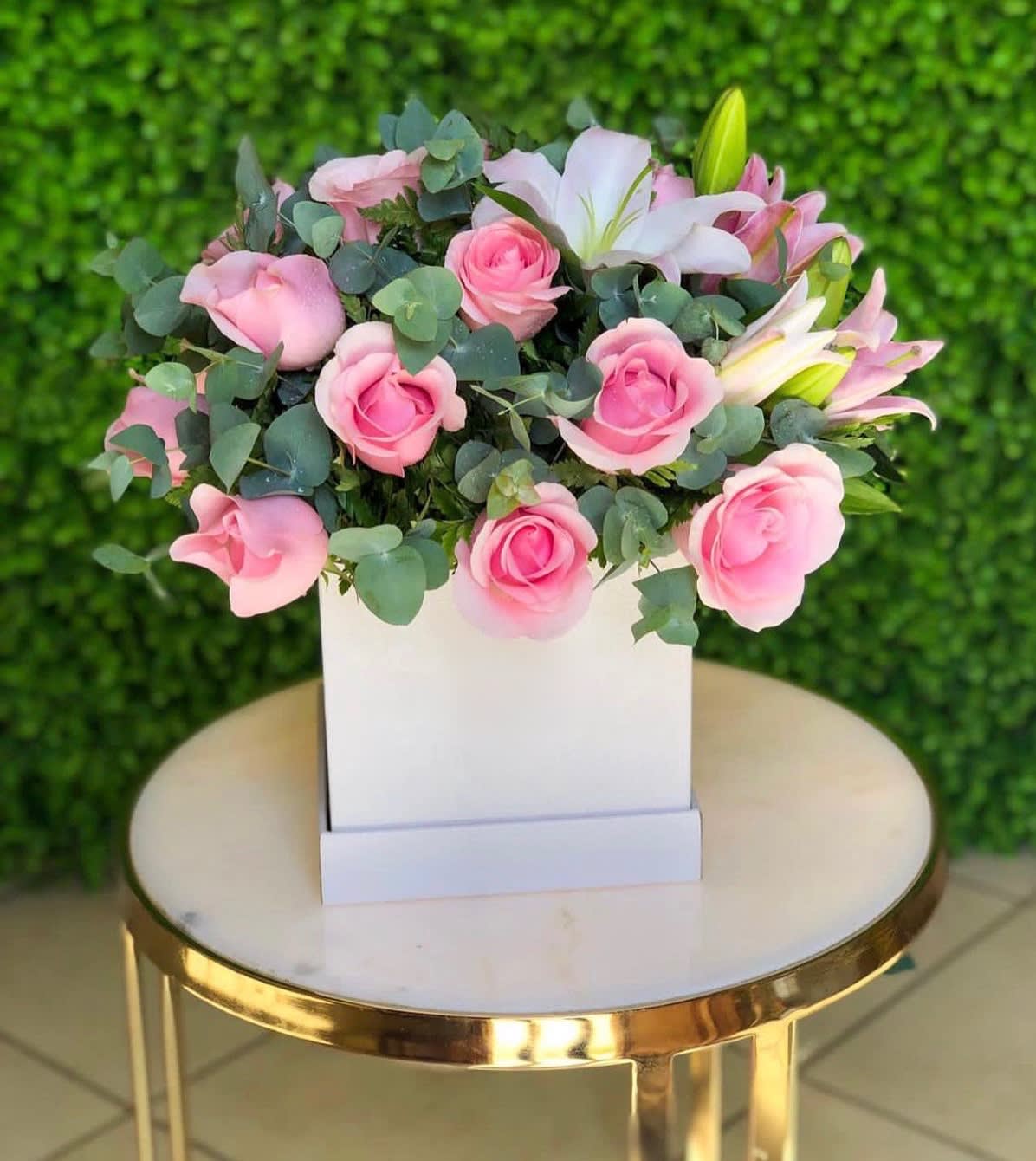 Pink roses and white lilies arranged in a white box