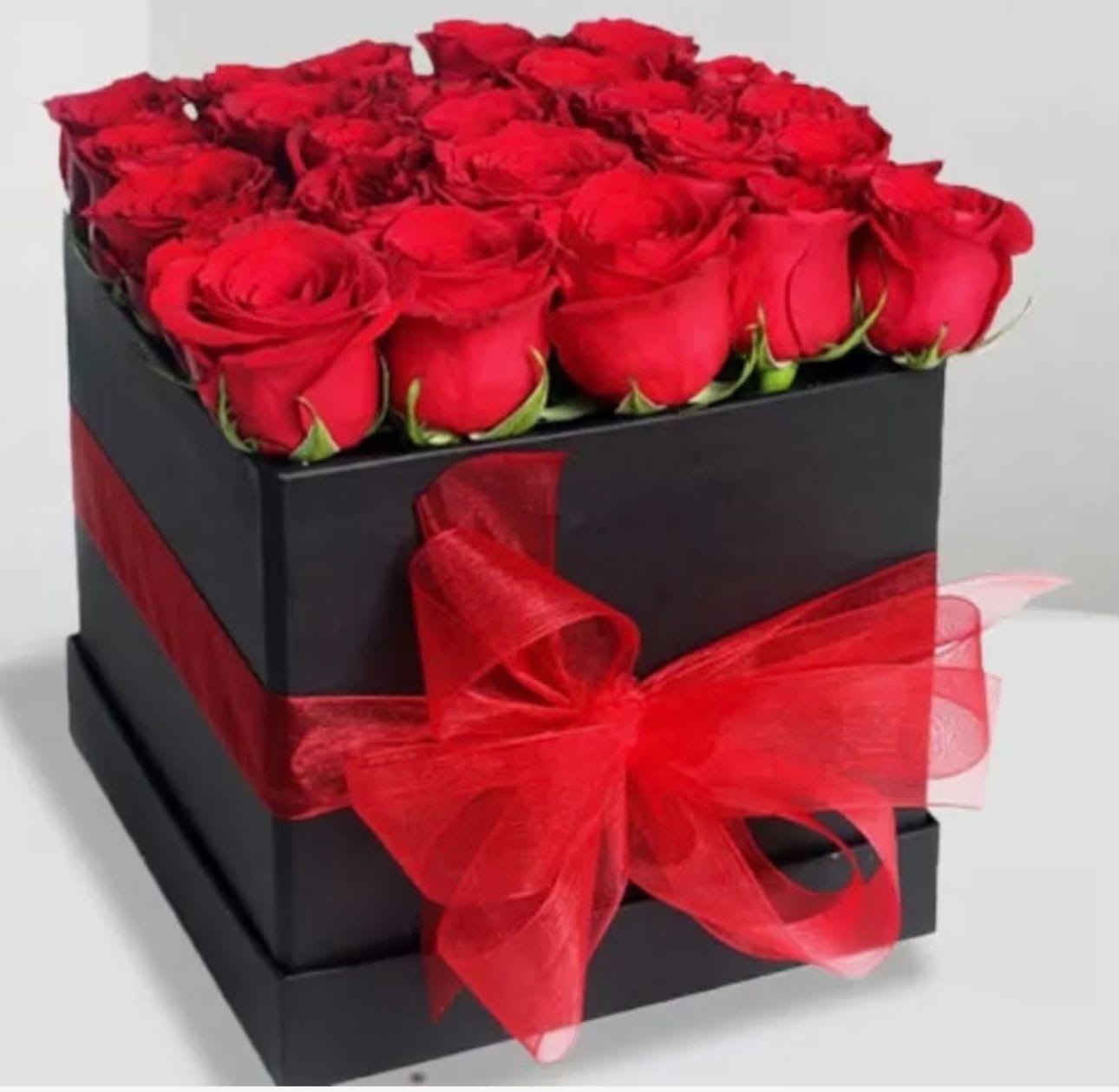 Red roses arranged in a black square box with a red ribbon bow