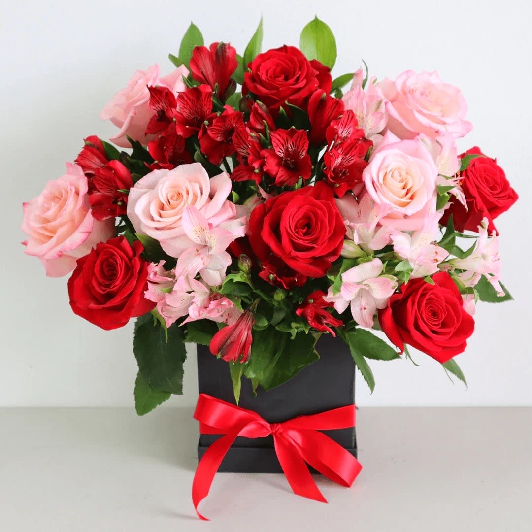 Bouquet of red and pink roses with red alstroemeria in a black box