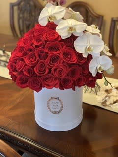 Red rose arrangement in a white hat box with white orchids