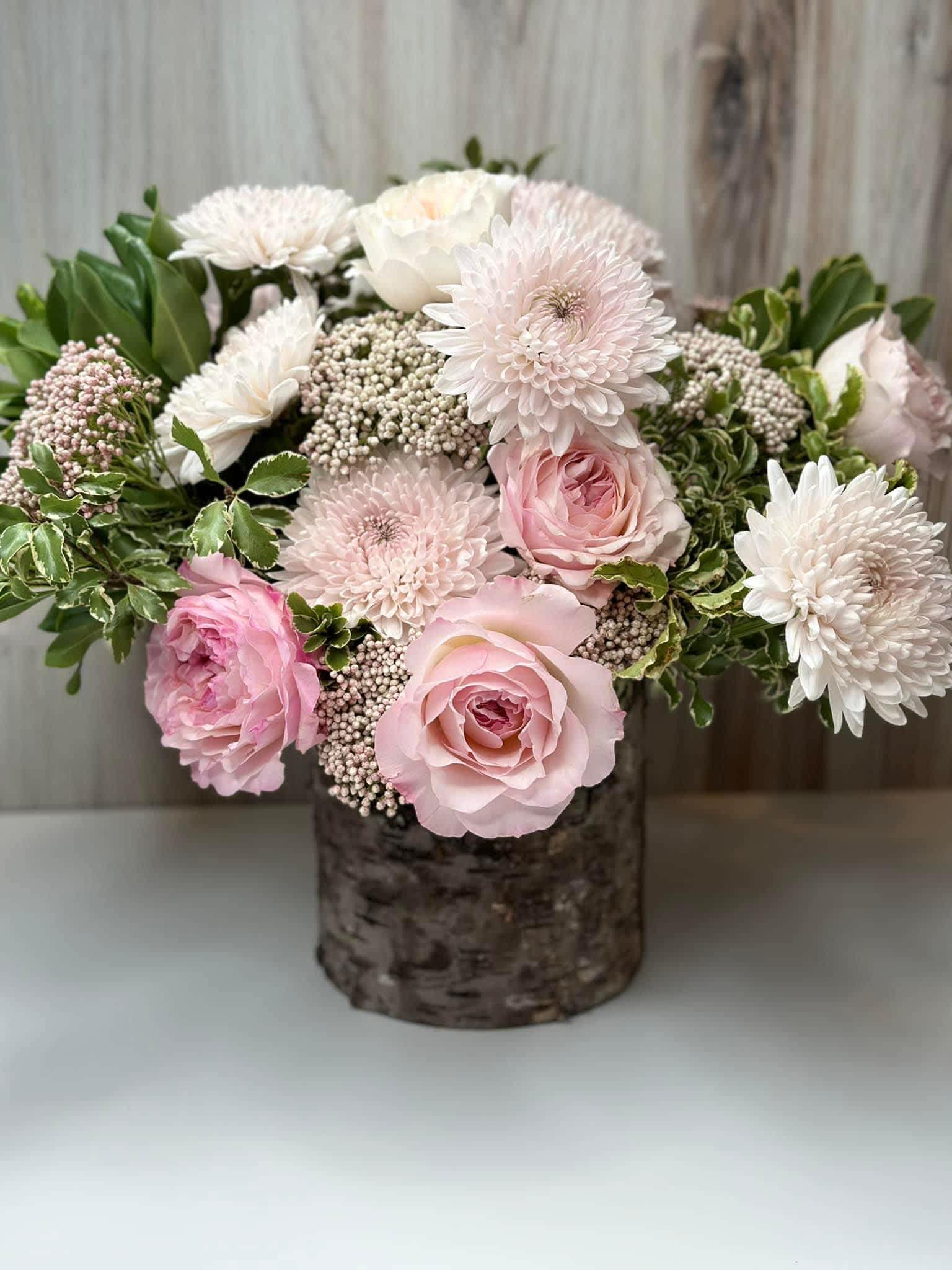 Pink and white roses with white chrysanthemums in a rustic vase