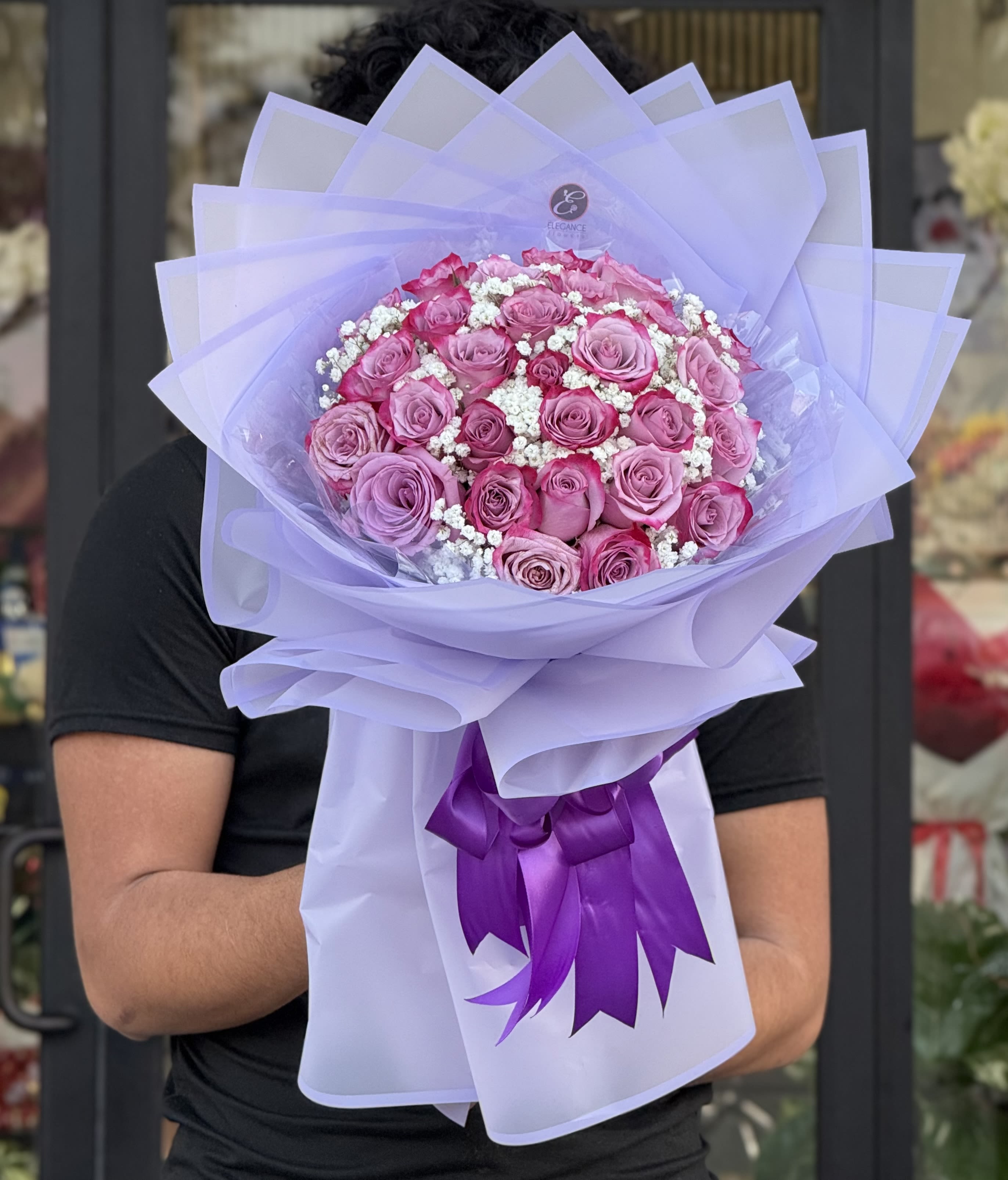 Bouquet of pink roses wrapped in lavender paper with a purple ribbon