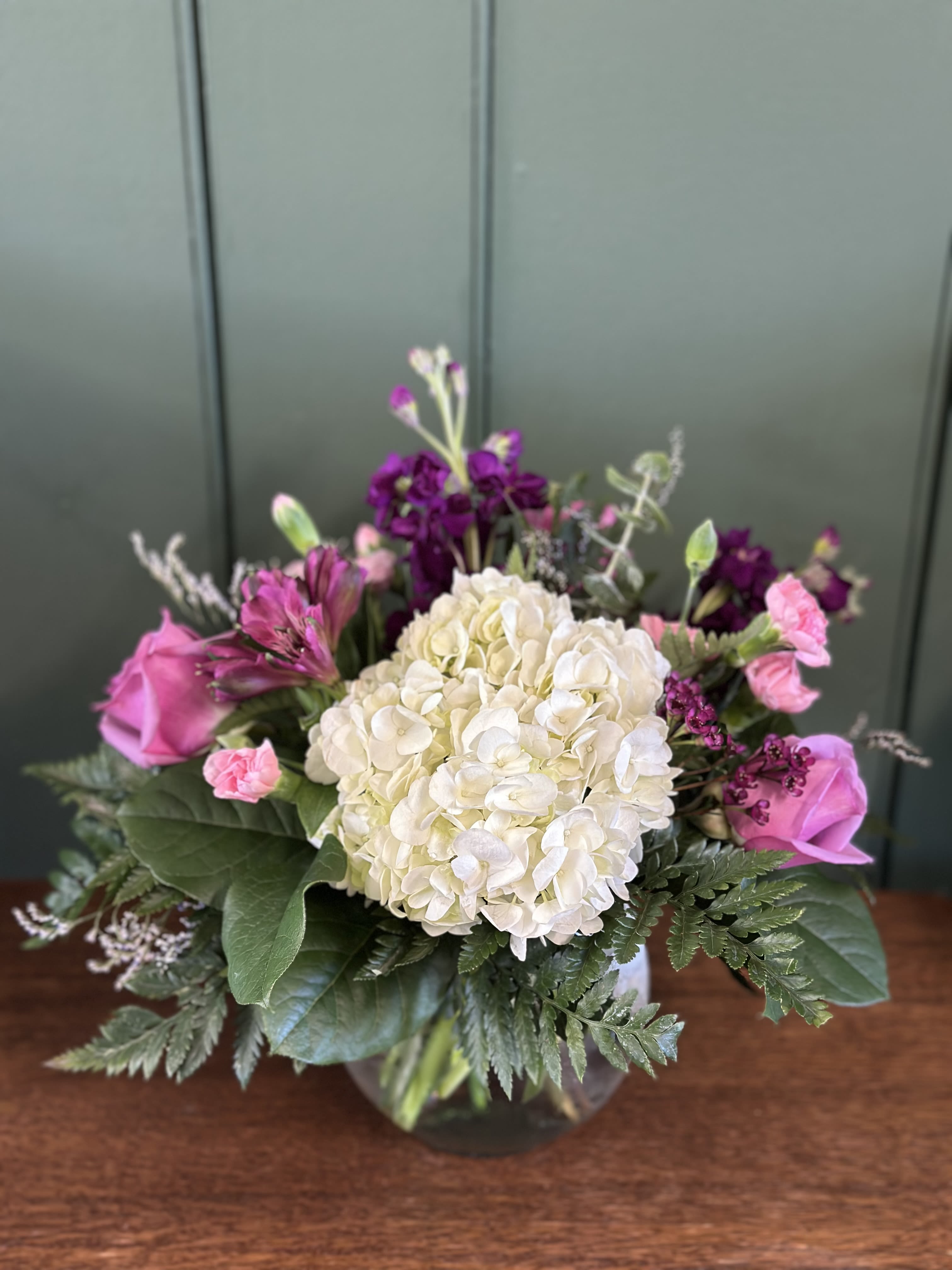 Love You More - A heartfelt arrangement designed with soft pink blooms, creamy white, and lush purples. A beautiful reminder of the words we never outgrow... Love you more!