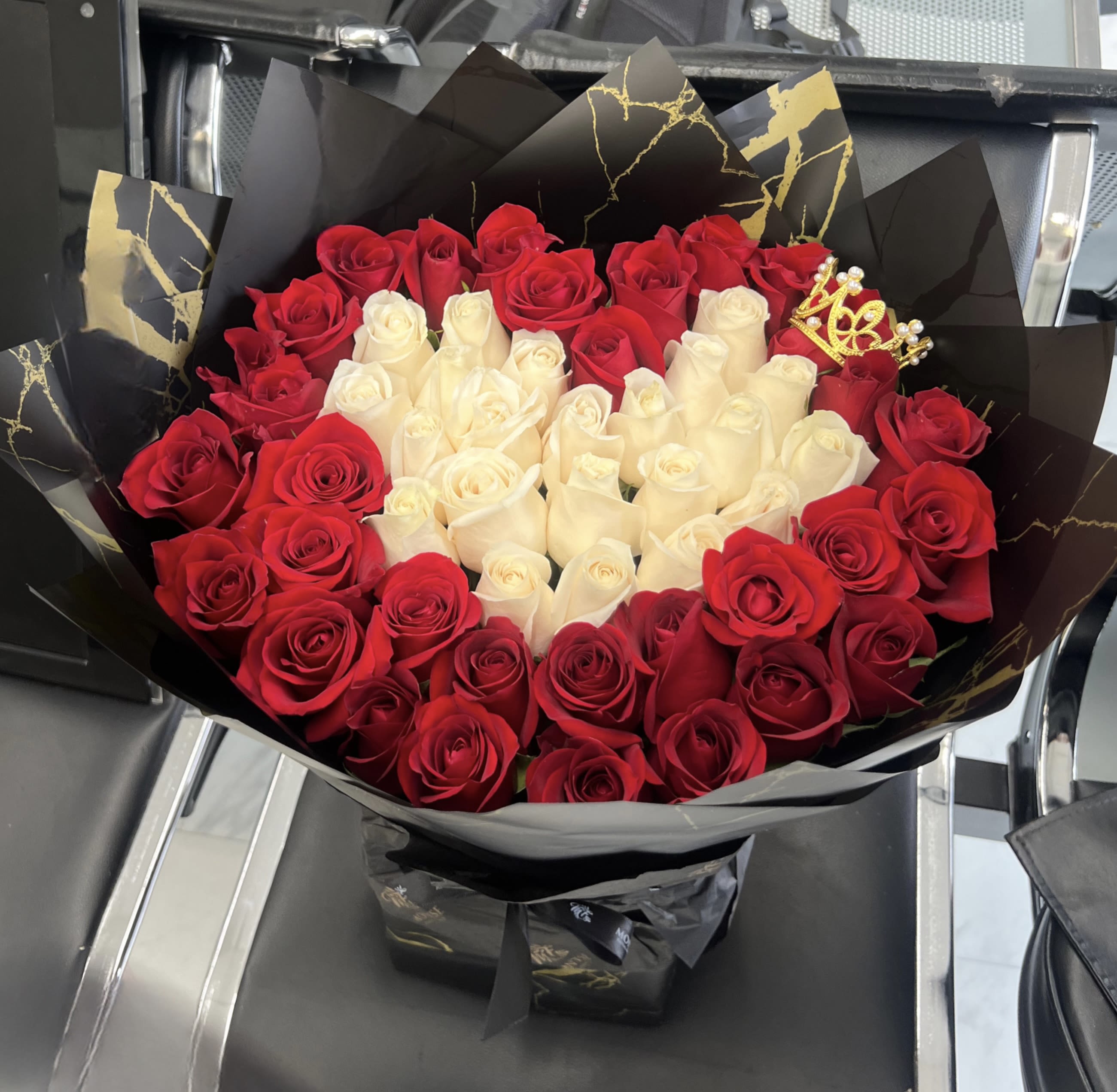 Bouquet of red and white roses wrapped in black paper with gold accents