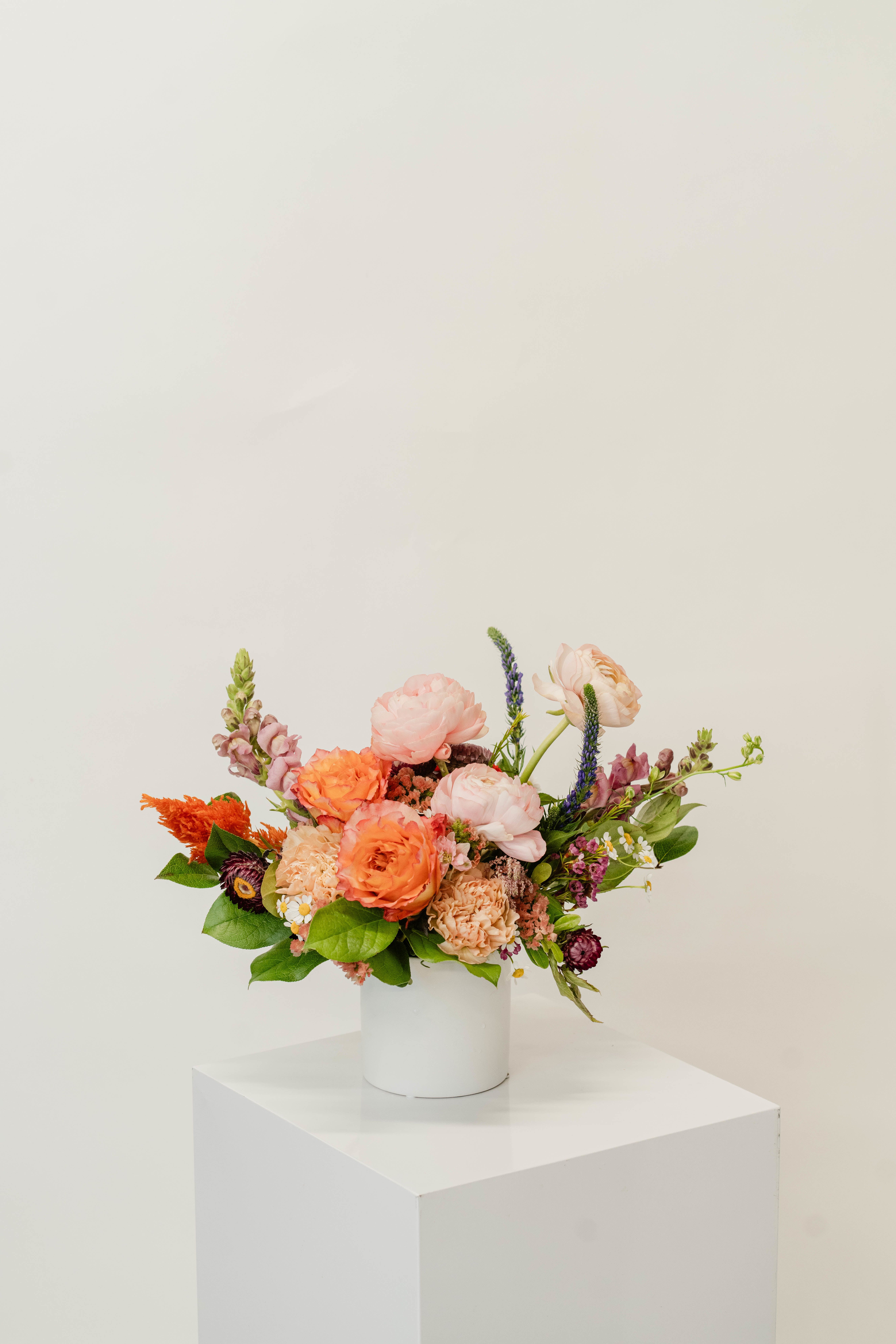 Colorful mixed flower arrangement in a white cylindrical vase