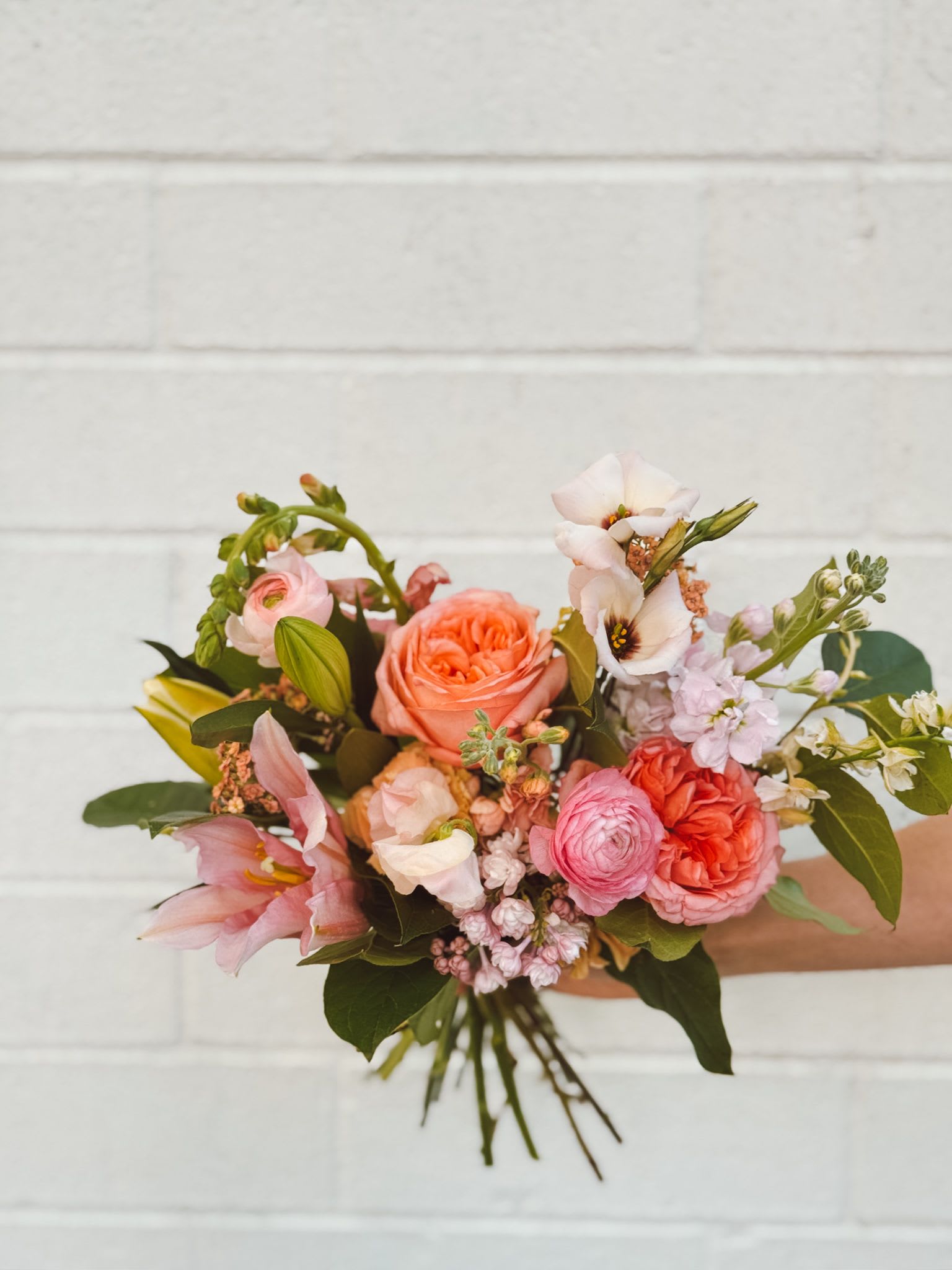 Hand-tied bouquet of pink and coral flowers with mixed blooms