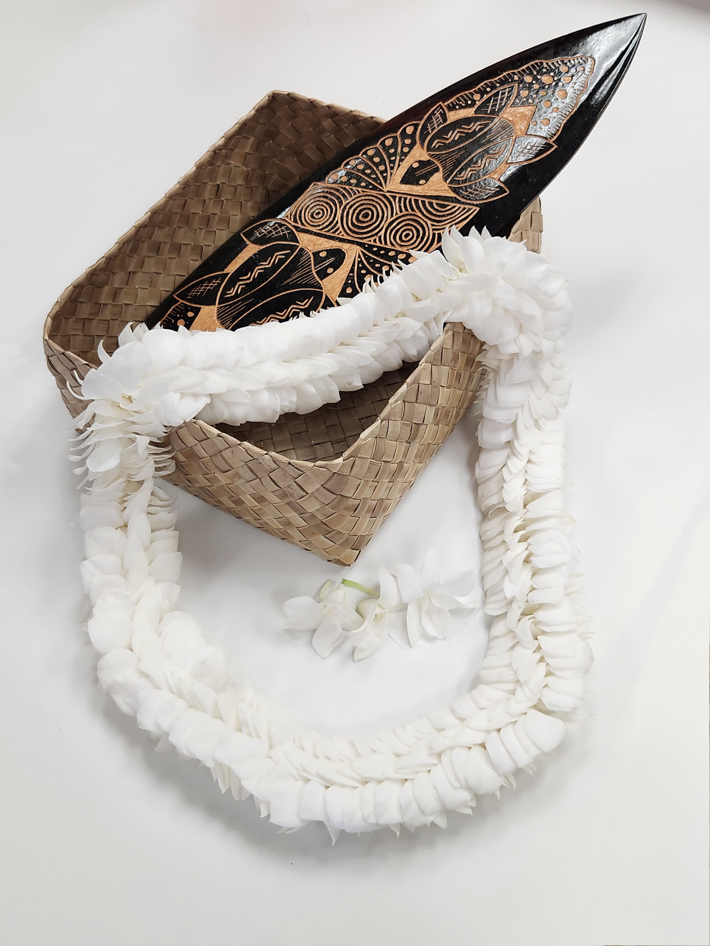 White flower garland draped over a woven basket with a carved wooden object