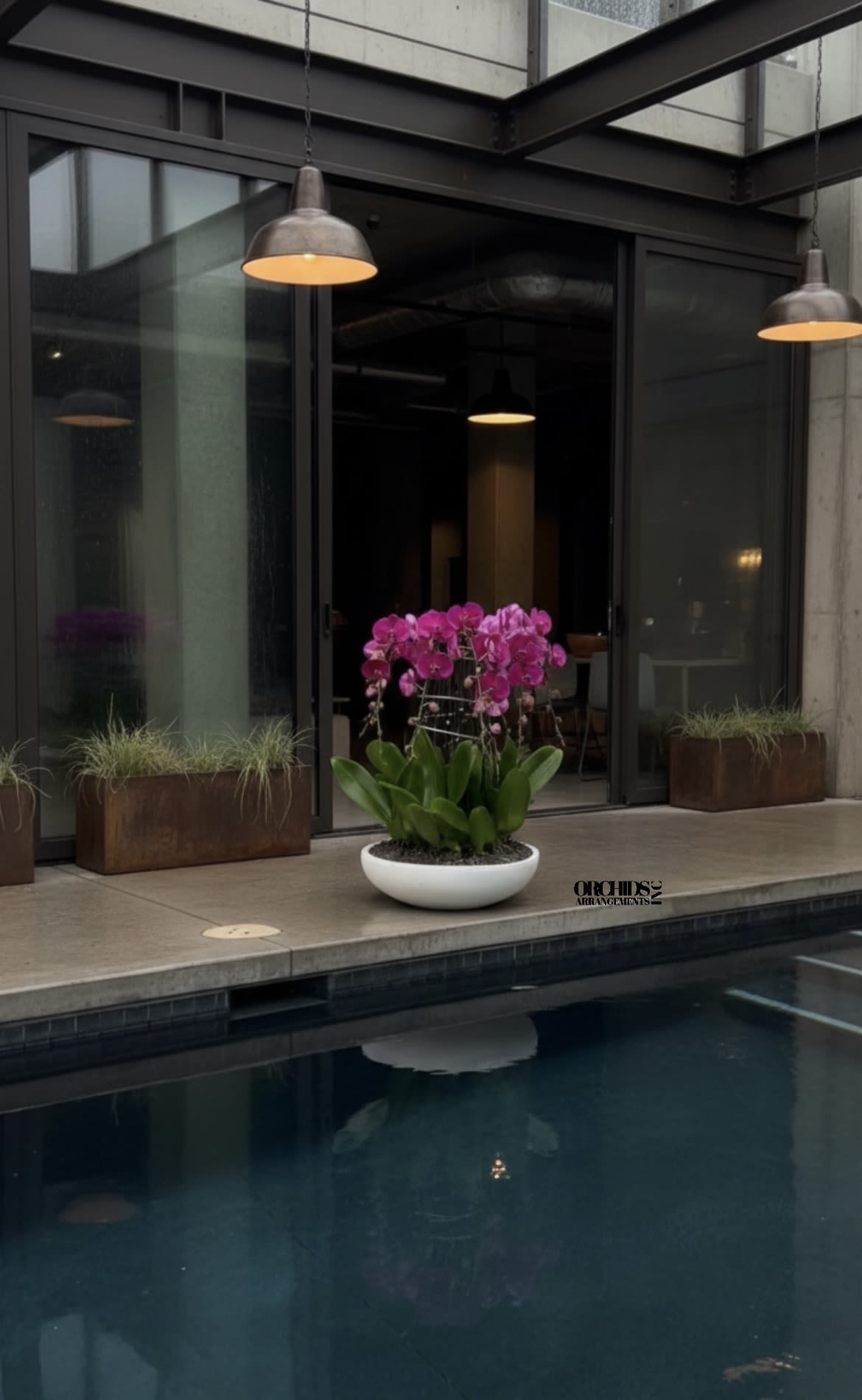 Pink orchids in a white bowl planter beside a pool