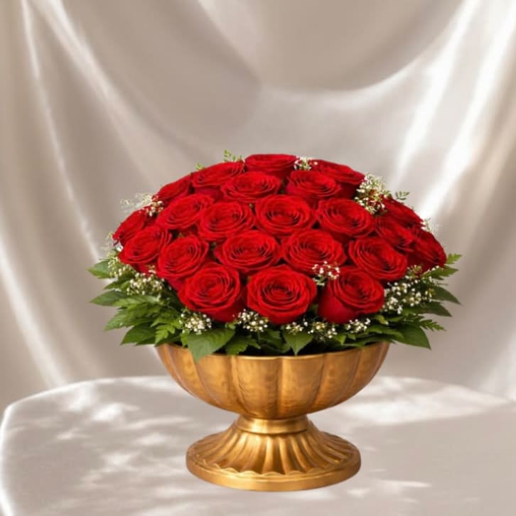 Golden Red Rose Centerpiece™ - A timeless and elegant arrangement featuring lush premium red roses, accented with delicate baby’s breath and fresh greenery, all designed in a classic gold pedestal bowl. This romantic centerpiece blends luxury and sophistication, making it a stunning statement for any special occasion. BloomNation’s Premium option includes a white orchid accent, adding an elevated, refined touch for an even more luxurious presentation.  Each piece is Designer’s Choice, created with fresh seasonal blooms. Flowers and colors may vary based on availability while maintaining the overall style and quality.  Better for: Valentine’s Day, anniversaries, romantic gestures, luxury gifts, engagement celebrations, I love you, elegant home décor, special moments, Mother’s Day, Women’s Day. 
