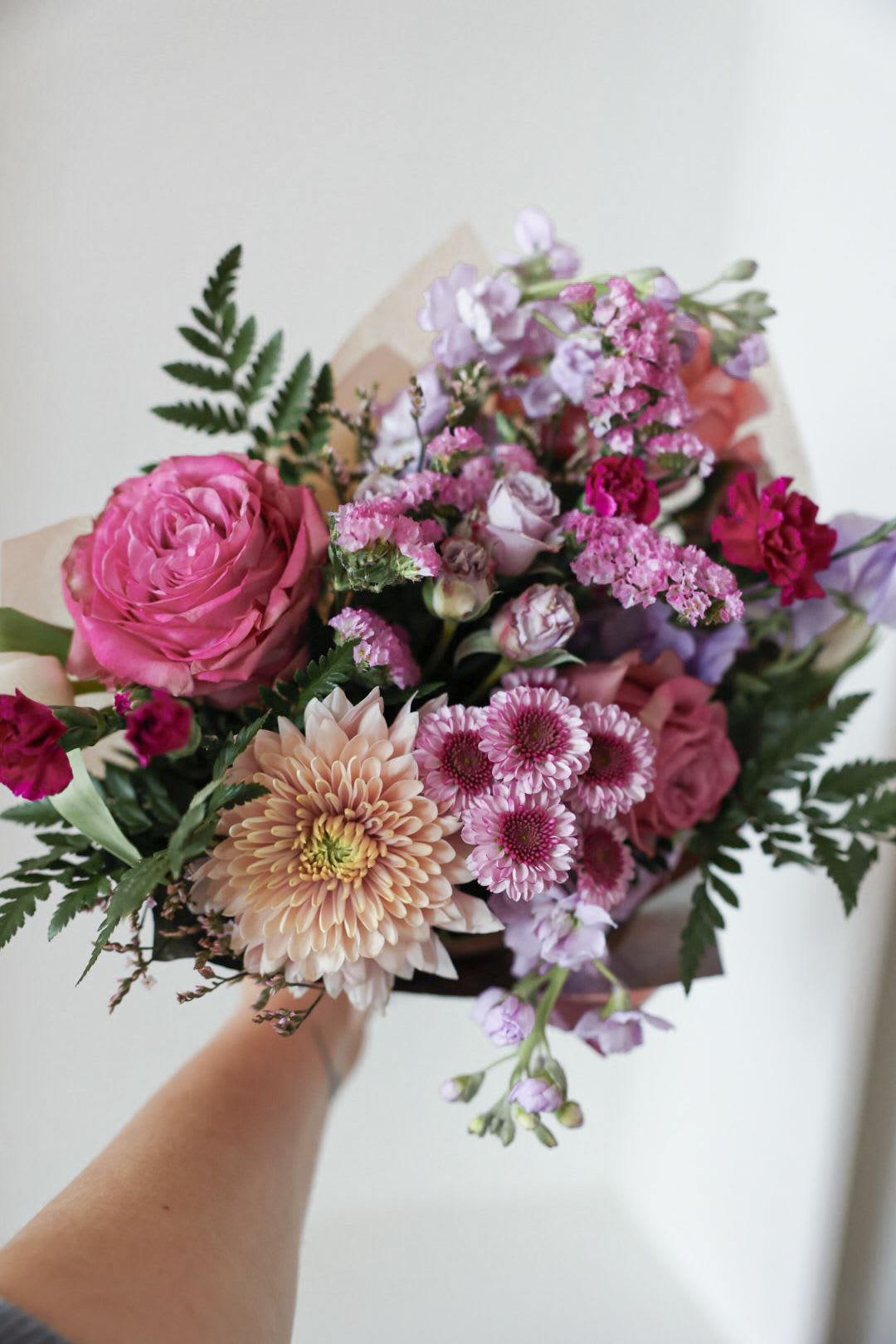 Handheld bouquet of pink and lavender flowers with mixed blooms