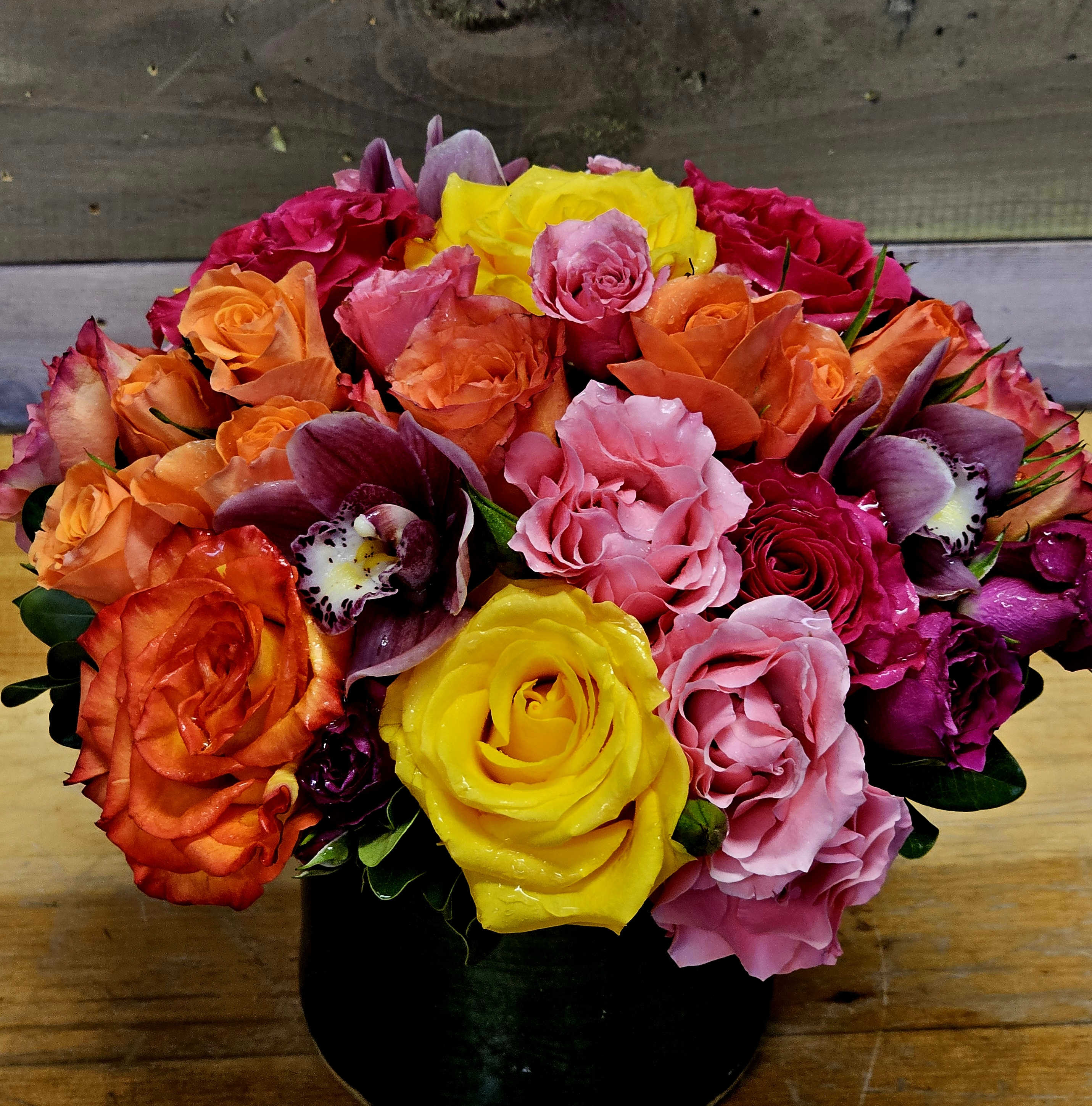 Colorful bouquet of roses and orchids in a black vase