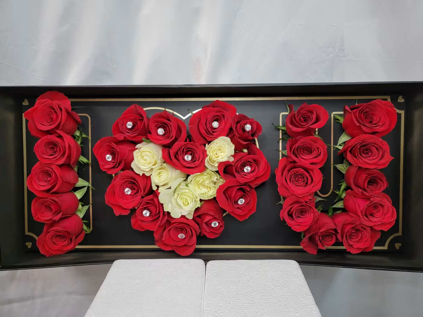 Red and white roses arranged in a heart shape on a black tray