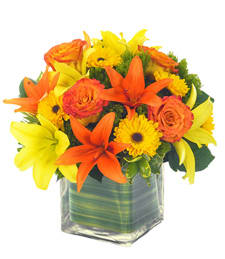 Orange and yellow flowers arranged in a clear square vase