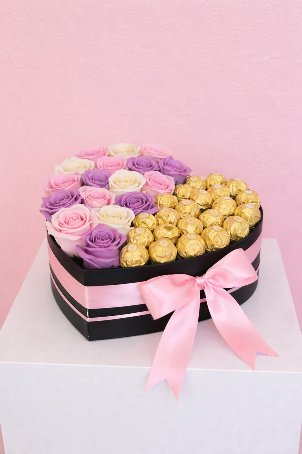 Berry Mom Half &amp; Half Box Black - A bold and luxurious heart-shaped arrangement featuring a stunning mix of pink, ivory, and soft lavender roses paired with premium Ferrero Rocher chocolates. Designed in an elegant black box and finished with a soft pink satin ribbon, this piece creates the perfect balance between romance and sophistication. Ideal for birthdays, anniversaries, or unforgettable surprises, this design is made to impress and indulge. Rose tones may vary slightly based on availability while maintaining the overall color palette.