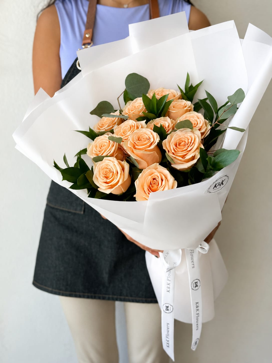 Dozen Peach Roses Bouquet - Dozen Peach Roses with greenery and decorative wrapping paper. All bouquets come without a vase. You can choose a vase in the add-on section.