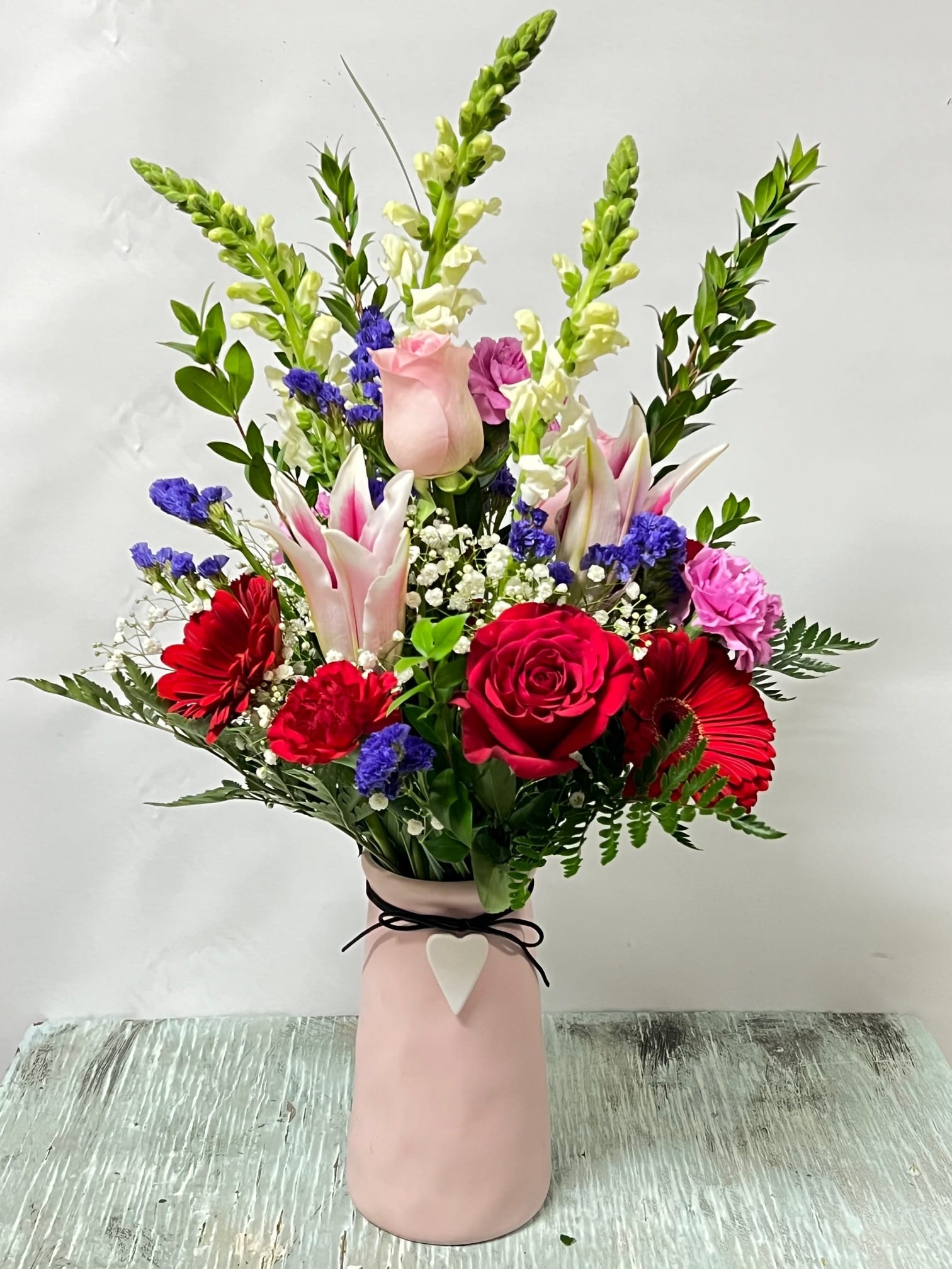 Mixed bouquet of red, pink, and white flowers in a pink vase